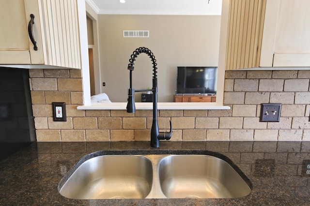 details featuring tasteful backsplash, visible vents, crown molding, dark stone counters, and a sink