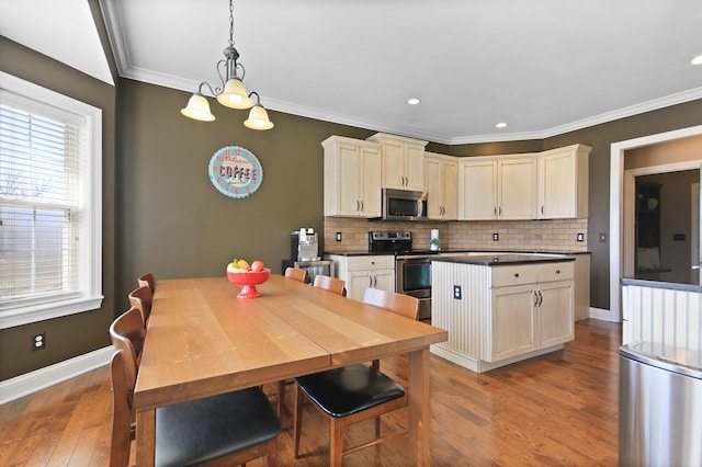 kitchen featuring dark countertops, ornamental molding, decorative backsplash, appliances with stainless steel finishes, and wood finished floors