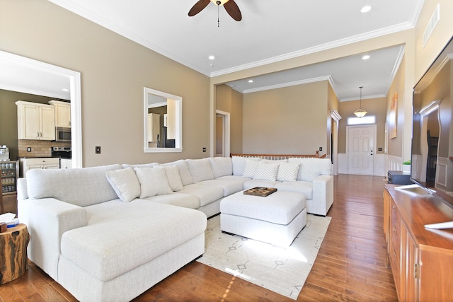 living area featuring wood finished floors, a ceiling fan, visible vents, recessed lighting, and wainscoting