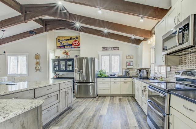 kitchen with a sink, stainless steel appliances, tasteful backsplash, and light wood finished floors