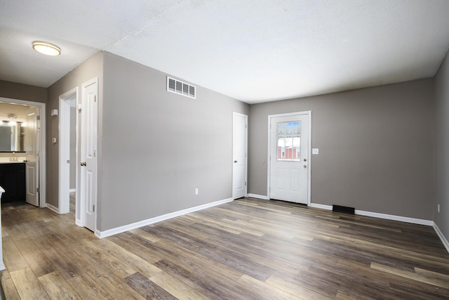 foyer entrance featuring visible vents, baseboards, and dark wood-type flooring