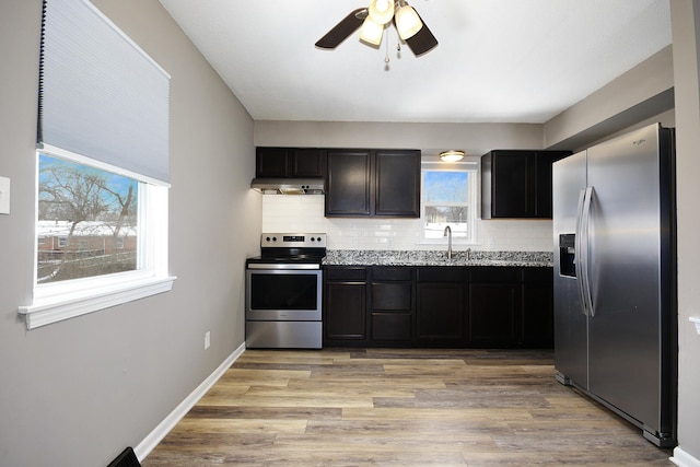 kitchen featuring backsplash, stainless steel appliances, extractor fan, and light wood-style flooring