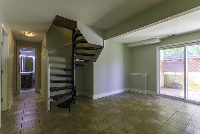 interior space with tile patterned flooring, visible vents, baseboards, and a textured ceiling