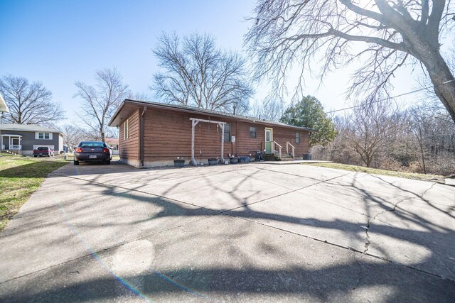 back of property featuring entry steps and concrete driveway