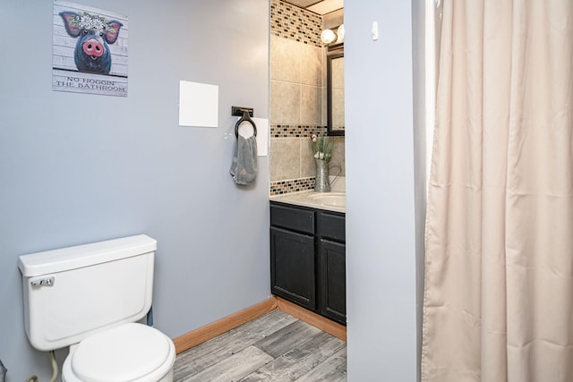 bathroom with toilet, vanity, baseboards, and wood finished floors