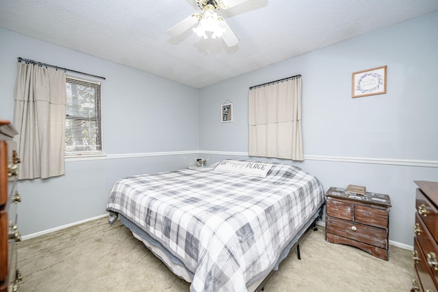 carpeted bedroom with a ceiling fan, baseboards, and a textured ceiling