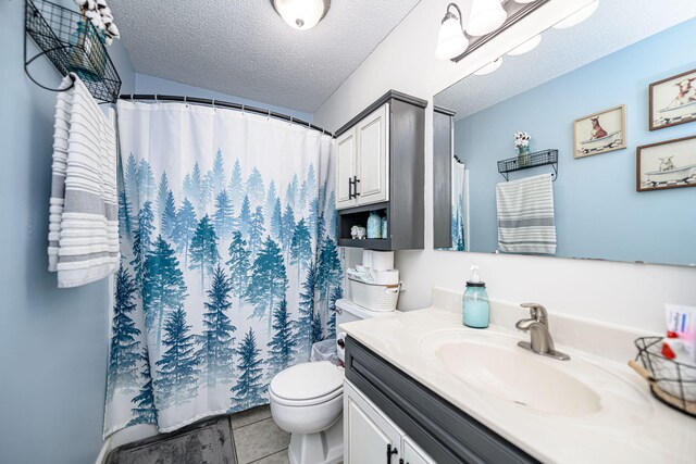 full bathroom featuring tile patterned flooring, toilet, vanity, and a textured ceiling