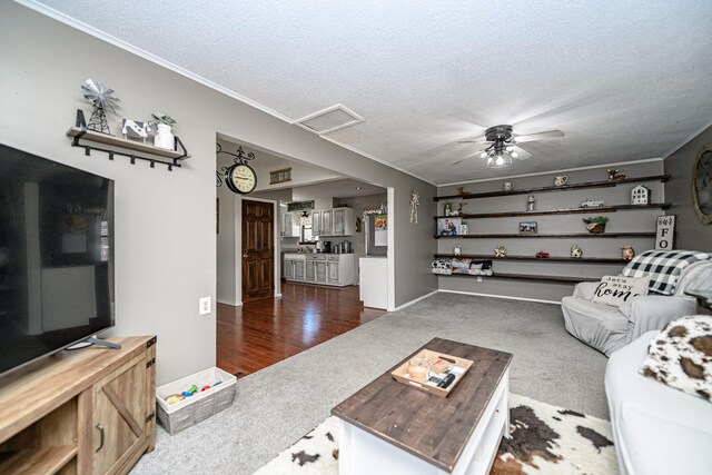 living room with visible vents, a textured ceiling, carpet floors, attic access, and ceiling fan