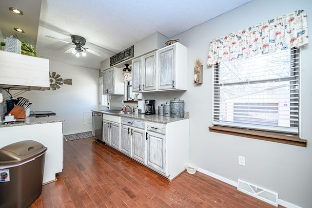 kitchen with visible vents, dark wood-type flooring, a ceiling fan, stainless steel dishwasher, and a textured ceiling