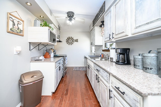 kitchen with dark wood-type flooring, a ceiling fan, a sink, stainless steel appliances, and baseboards