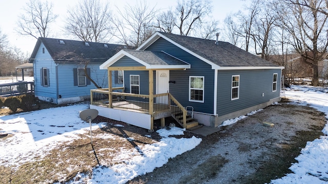 view of front of home featuring a wooden deck and roof with shingles