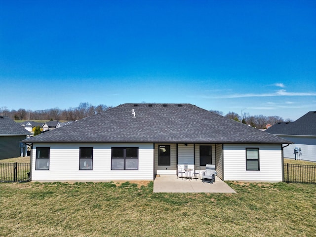 rear view of house featuring a patio, a lawn, roof with shingles, and fence