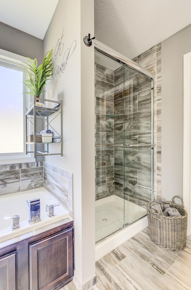 bathroom with a textured ceiling, a bath, and a shower stall