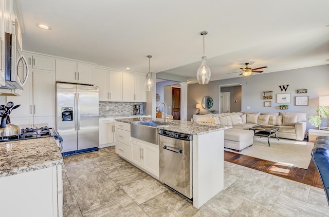 kitchen with a ceiling fan, a sink, open floor plan, white cabinetry, and stainless steel appliances