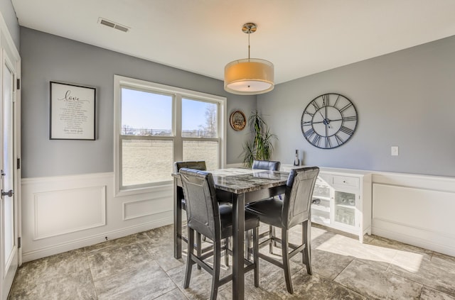 dining area featuring visible vents, wainscoting, and a decorative wall