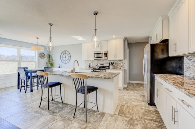 kitchen with a sink, a breakfast bar area, appliances with stainless steel finishes, and white cabinets