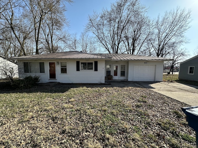 ranch-style house featuring an attached garage, driveway, and metal roof