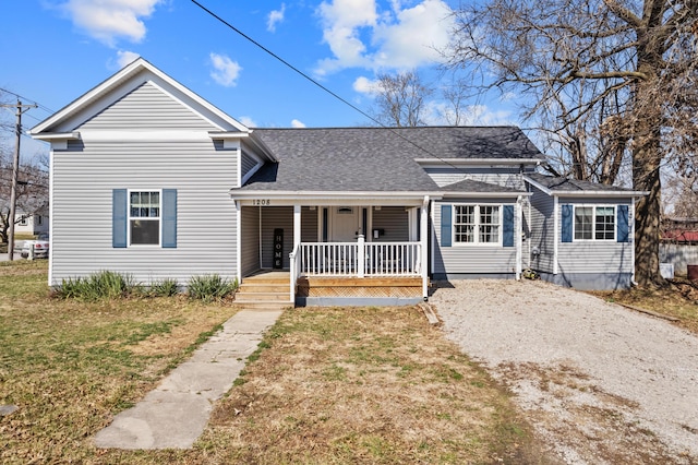 traditional-style home featuring a front yard, covered porch, driveway, and a shingled roof