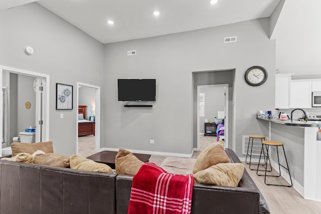 living room with recessed lighting, visible vents, baseboards, and light wood-style flooring