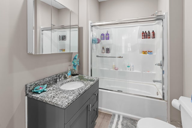 bathroom featuring combined bath / shower with glass door, toilet, vanity, and wood finished floors