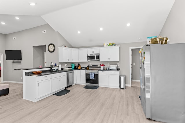 kitchen with dark countertops, vaulted ceiling, a peninsula, stainless steel appliances, and a sink