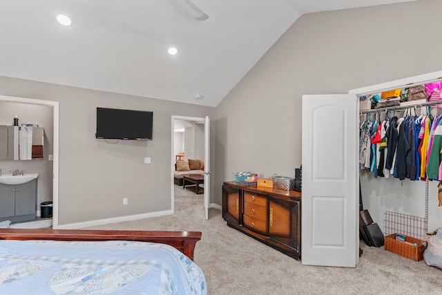 carpeted bedroom featuring baseboards, lofted ceiling, a closet, ensuite bath, and a sink