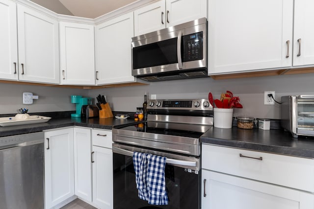 kitchen featuring dark countertops, white cabinets, a toaster, and appliances with stainless steel finishes