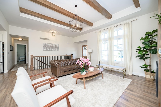 living area with visible vents, baseboards, light wood-style floors, beamed ceiling, and a chandelier