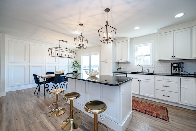 kitchen with dark countertops, a chandelier, a healthy amount of sunlight, and a breakfast bar