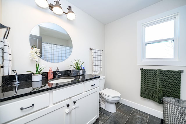 bathroom featuring toilet, vanity, and baseboards