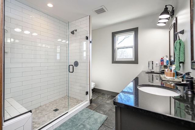 full bath with visible vents, double vanity, a stall shower, a sink, and toilet