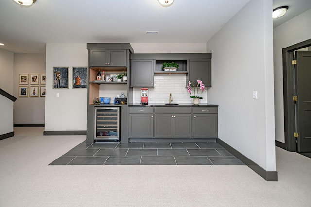 bar featuring visible vents, wine cooler, indoor wet bar, decorative backsplash, and a sink