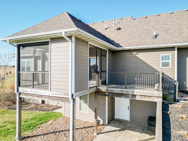 rear view of house with roof with shingles and a sunroom