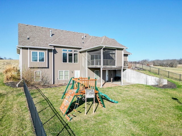 back of property featuring a shingled roof, a lawn, a fenced backyard, and a sunroom