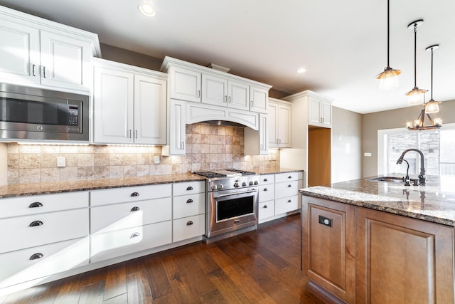 kitchen featuring dark wood-style floors, a sink, appliances with stainless steel finishes, white cabinetry, and tasteful backsplash