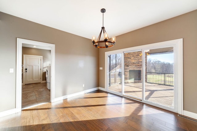 unfurnished dining area with visible vents, baseboards, an inviting chandelier, washer / clothes dryer, and wood-type flooring