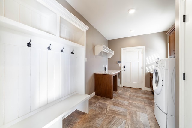 laundry area featuring baseboards, cabinet space, washer / clothes dryer, and stone finish floor