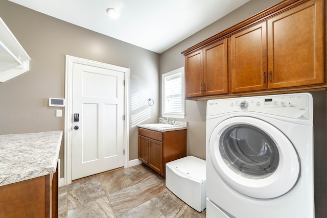 washroom featuring washing machine and dryer, cabinet space, baseboards, and a sink