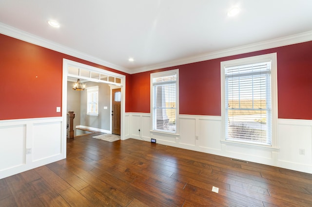 spare room featuring crown molding, an inviting chandelier, wainscoting, and hardwood / wood-style flooring