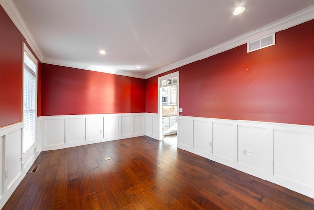 empty room featuring visible vents, crown molding, a wainscoted wall, and dark wood-style flooring