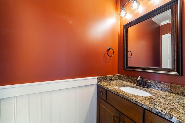 bathroom with a wainscoted wall, ornamental molding, and vanity