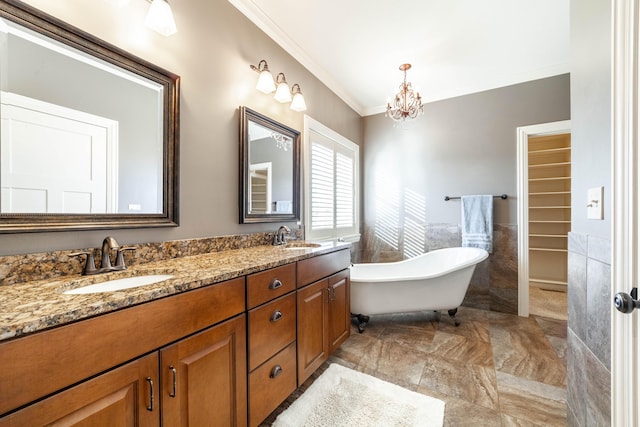 bathroom featuring a notable chandelier, a freestanding bath, crown molding, and a sink