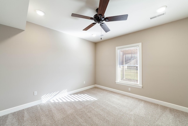 carpeted spare room featuring visible vents, ceiling fan, and baseboards