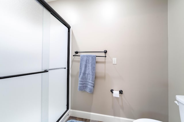 bathroom featuring a shower stall, toilet, and baseboards