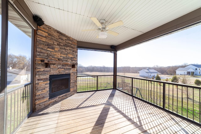 wooden terrace with a ceiling fan and an outdoor stone fireplace