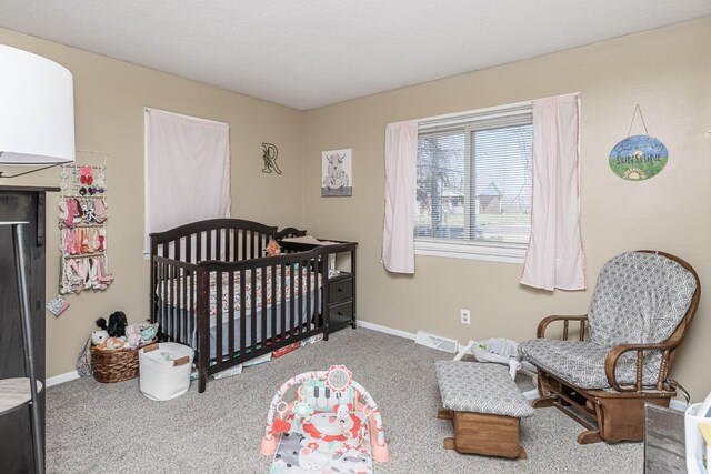 carpeted bedroom featuring visible vents, a crib, a textured ceiling, and baseboards