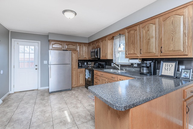 kitchen featuring dark countertops, baseboards, light tile patterned floors, appliances with stainless steel finishes, and a sink