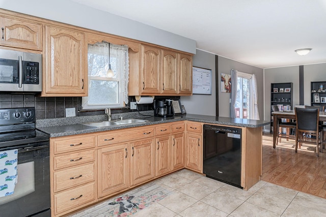 kitchen featuring a sink, dark countertops, black appliances, and a healthy amount of sunlight