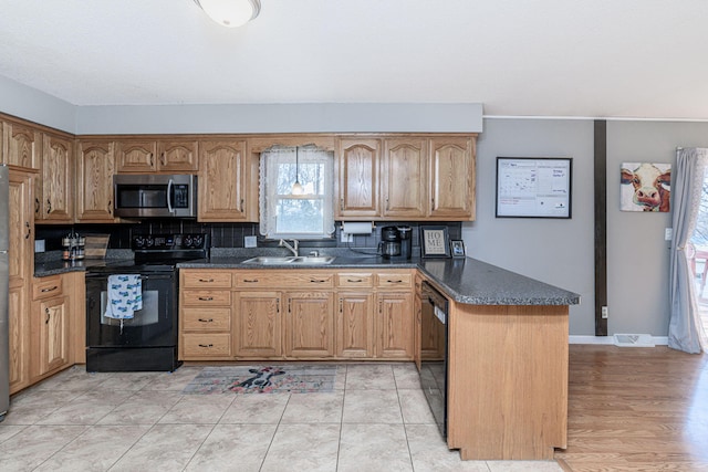 kitchen with visible vents, black appliances, a sink, a peninsula, and baseboards