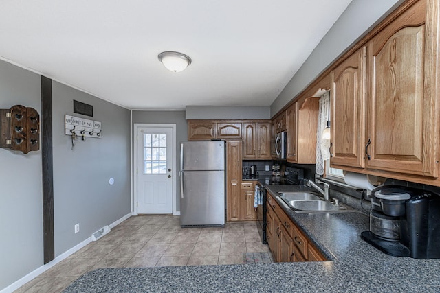 kitchen with dark countertops, visible vents, baseboards, appliances with stainless steel finishes, and a sink